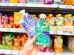 hand holding two pouches of cerebelly baby food puree in walmart aisle