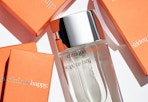 a bottle of perfume next to orange boxes