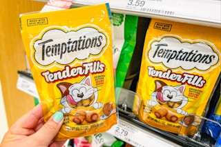 hand holding a bag of temptations cat treats in front of other pet treats