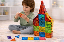 child playing with magnetic tiles on the floor