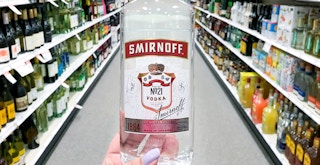 hand holding smirnoff no 21 bottle in store aisle