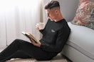 Man sitting up against a couch drinking a cup of coffee wearing the Xtreme Heat Compression Pants & Shirt in black