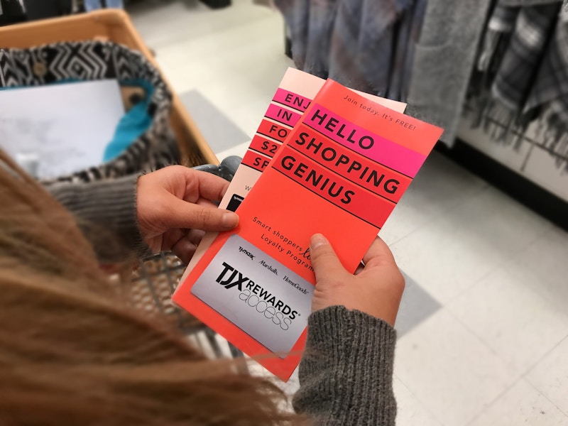 hand holds TJ Maxx brochure for rewards card entitled "Hello Shopping Genius