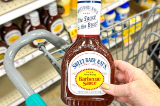 hand holding a bottle of sweet baby rays bbq sauce