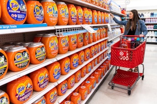 Woman pushing a Target shopping basked looking at Tide laundry detergent products.
