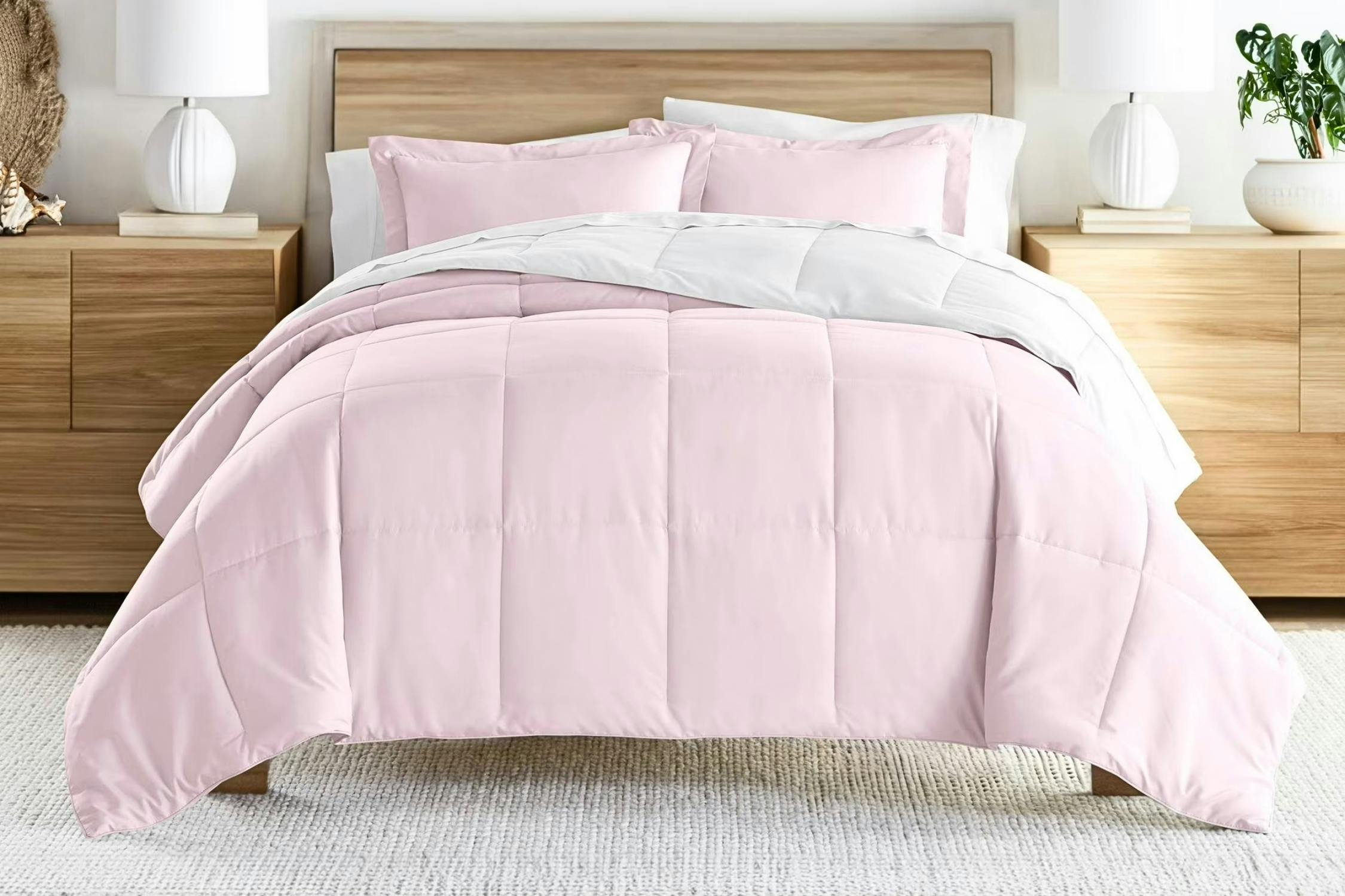 Lifestyle image of the blush/white reversible comforter set from Noble Linens 
