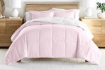 Lifestyle image of the blush/white reversible comforter set from Noble Linens