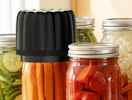 a mason jar sealer machine on a mason jar full of vegetables
