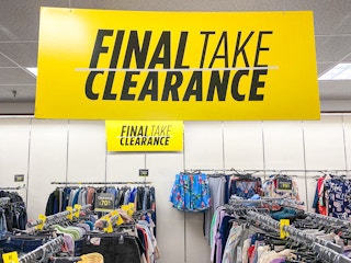A large JCPenney clearance sign hanging above racks of clothing.