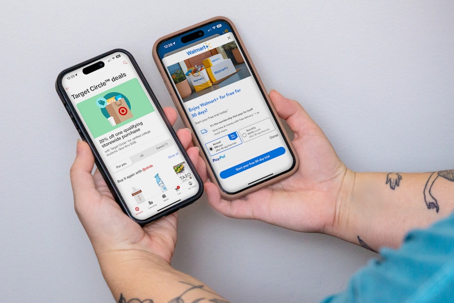 someone holding up two phones, one displaying the Walmart app and the other displaying the Target app