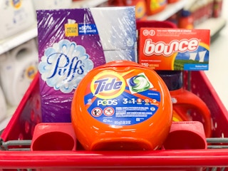 Box of Puffs facial tissues, pack of Tide Pods, and box on Bounce dryer sheets together in the front basket of a Target shopping cart
