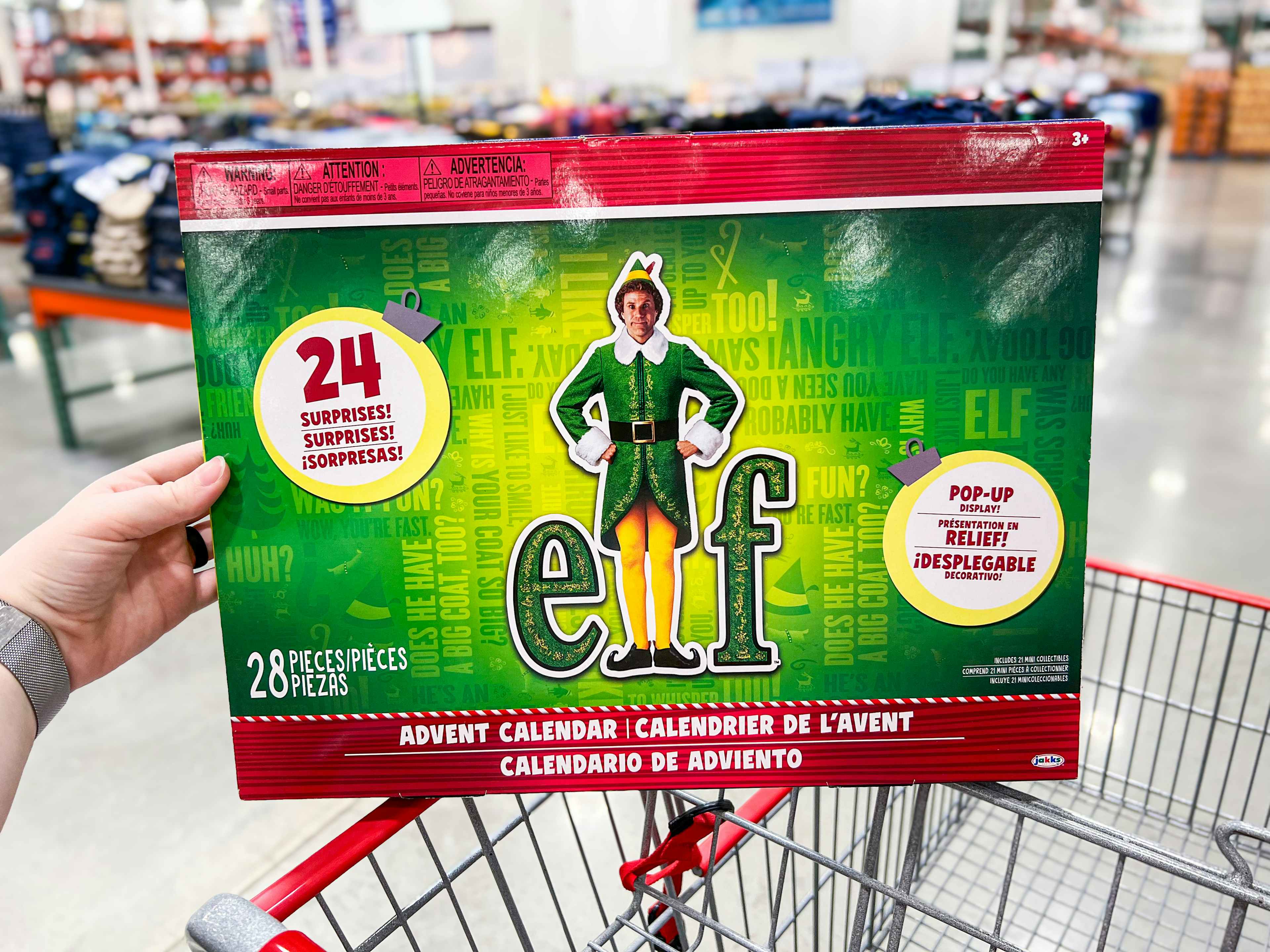 person holding an elf advent calendar over a costco cart