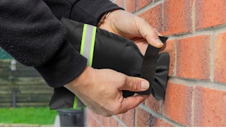 hands covering an outdoor faucet with a cover