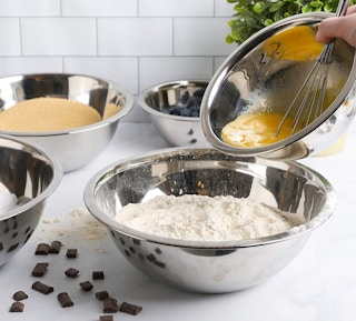 stainless steel mixing bowls with flour and egg inside