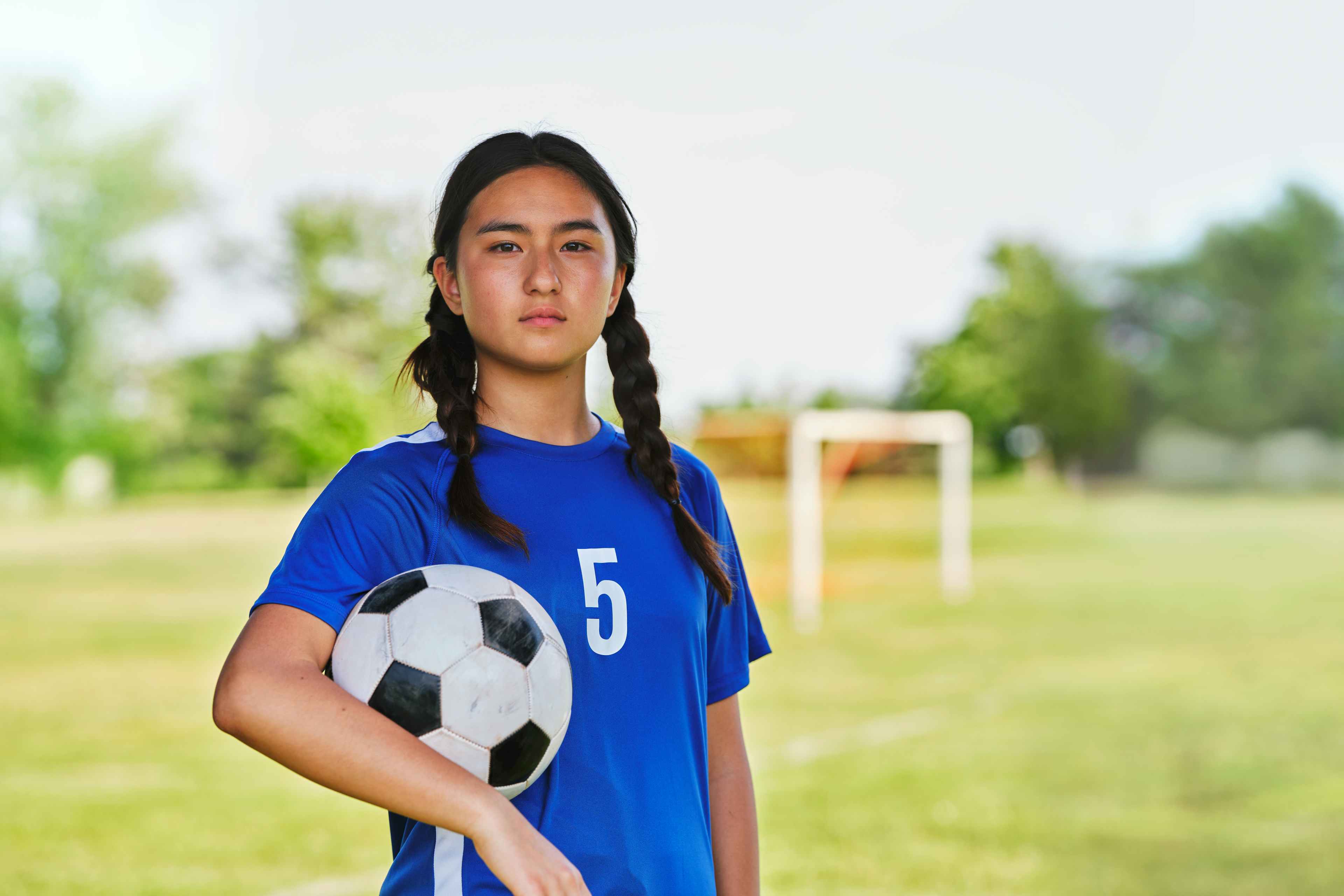 a young girl in a soccer uniform on a field 