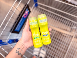 hand holding two ban deodorants over walmart cart