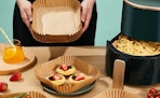 Square Air Fryer Disposable Paper Liners on a Table With Food