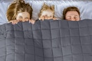 Lifestyle image of three people peeking out from a  Teler Weighted Queen Blanket
