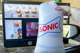 person holding a bag of sonic ice in the drive-up near the menu