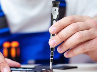 a person screwing in a screw with a screwdriver