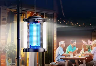 bug zapper hanging on a pole while a family eats dinner outside