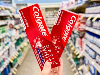 hand holding two boxes of colgate optic toothpaste