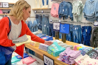 A woman looking at girls t-shirts inside Gap factory outlet