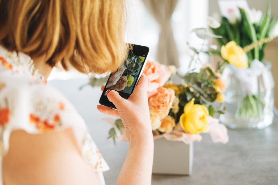 A person taking a photo of a cute handmade flower arrangement