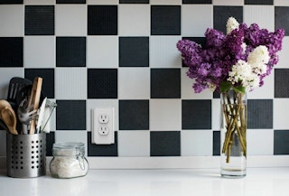 checkered backsplash with flowers on countertop and smart plug