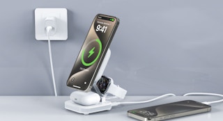 an iPhone, AirPods, and Apple Watch on a charging stand