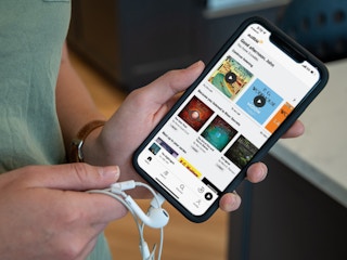 person with headphones and phone showing amazon audible audiobook marketplace