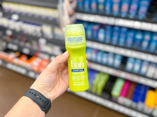 hand holding up a bottle of ban deodorant in the aisle at the grocery store