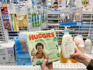 a person holding up huggie diapers and aveeno lotion