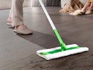 a person sweeping the floor with a dust mop