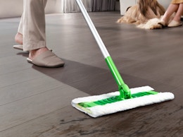 a person sweeping the floor with a dust mop