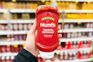 hand holding a bottle of hunts ketchup