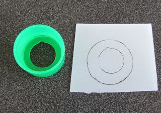 a lotion bottle little and paper with a trace of the top on it.