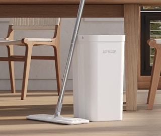 a flat mop and bucket in a room next to a wooden table and chairs