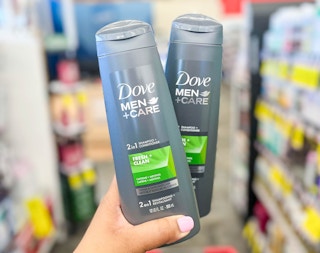 hand holding two bottles of Dove Men+Care 2in1 Shampoo and Conditioner
