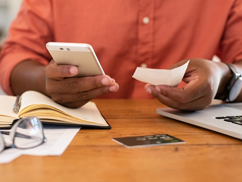 a person holding an iphone and a piece of paper