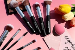 a makeup brush set on a pink surface