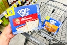 person holding a box of pop tarts over a cart with another box in it