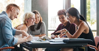 college students laughing and studying together at table feature
