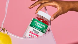 a hand putting a bottle of vitamins in a purse