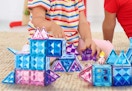 childing playing with blue, purple, and pink magnetic tiles