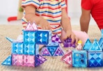 childing playing with blue, purple, and pink magnetic tiles
