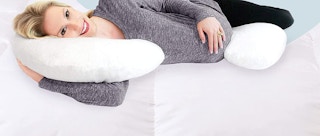 A pregnant woman laying on a pregnancy pillow