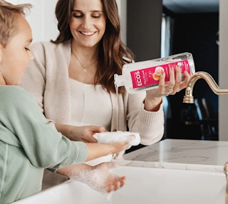 a woman pour soap in a kid's hand