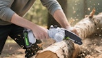 a person using a mini chainsaw on a log