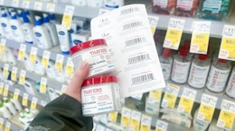 person holding 2 bottles of thayers blemish pads with a stack of paper coupons